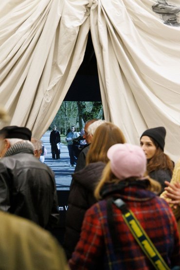Ein großes Zelt steht im Raum, Menschen gehen darunter hindurch.