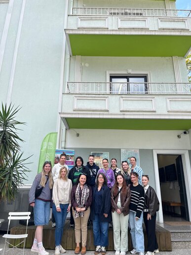Eine Gruppe steht für ein Foto vor einem Gebäude