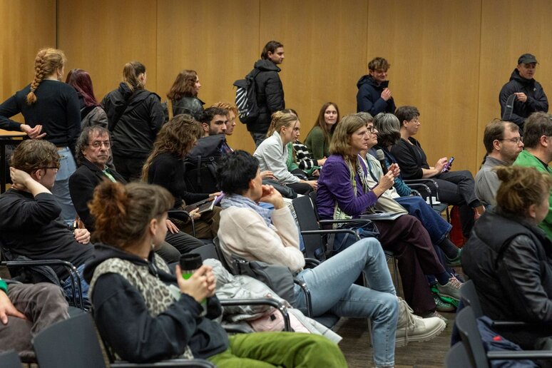 Eine Frau mitten im Publikum hat das Mikrofon und stellt eine Frage.