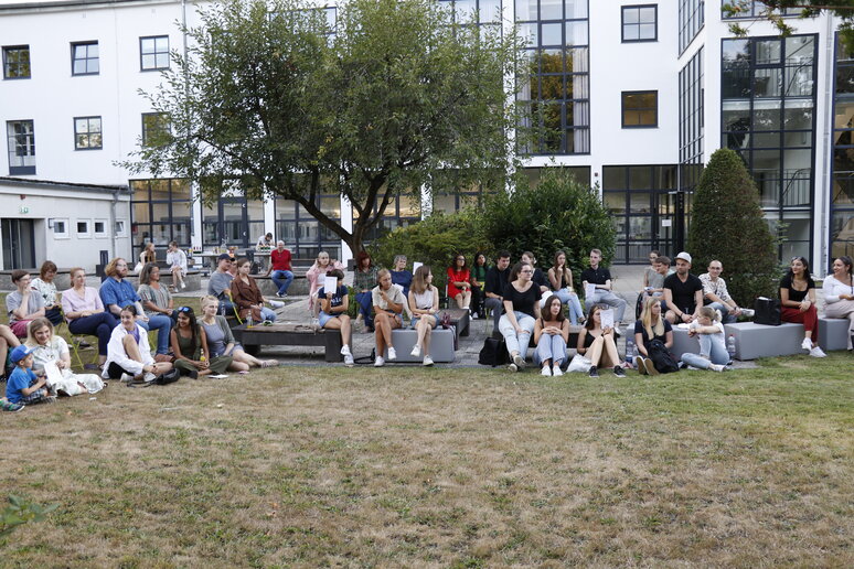 Eine Gruppe Studierender sitzt auf der Wiese im Innenhof der katho