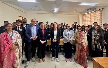 Die drei Kolleg_innen aus Münster stehen zusammen mit Kolleginnen und Studierenden des Law Departments in einem Raum.