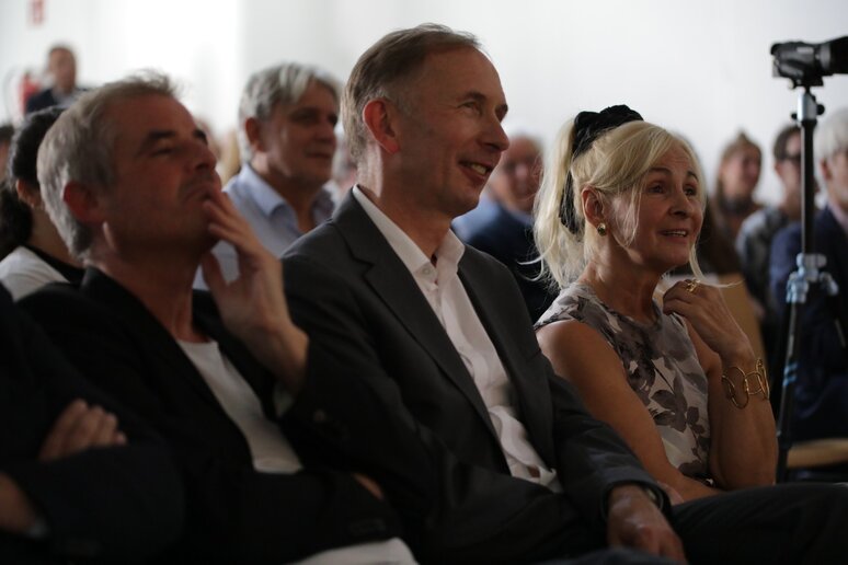 Die drei sitzen in der ersten Reihe und lauschen einer Rede