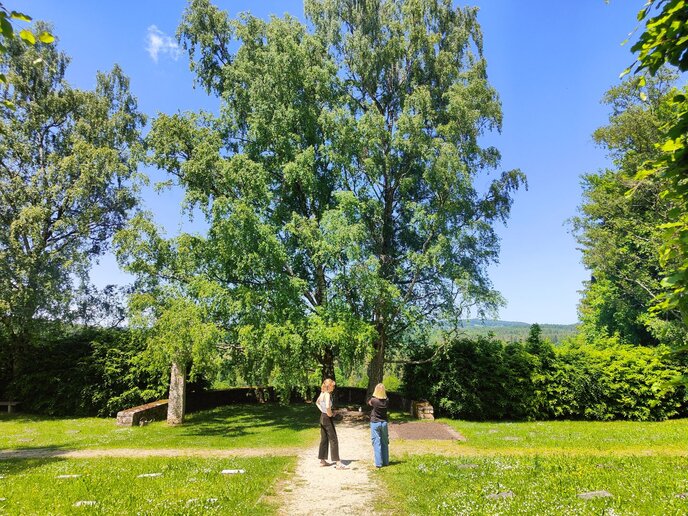 Zwei Besucherinnen stehen im Alphabetgarten in der Sonne.