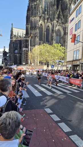 Mehrere Marathonläufer auf der Straße vor dem Kölner Dom.