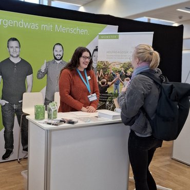 Eine Frau berät an einem Messestand eine interessierte Besucherin.