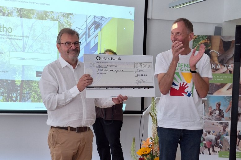 Dieter Dücker, Lehrer am Irmgardis-Gymnasium in Köln-Bayenthal, überreicht einen Spendenscheck über 9.000 Euro Das Geld hatte die Schüler_innen beim Spendenlauf eingenommen.