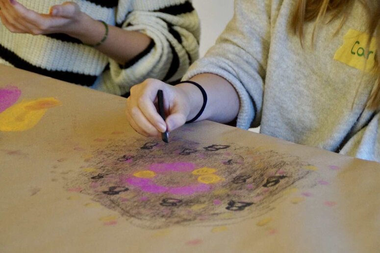 Eine Schüler:in gestaltet mit einen Wachsmalbild ein Bild.