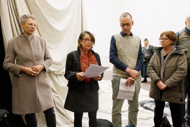 Vier ältere Menschen stehen mit Zetteln vor der Tuch-Gestell Konstellation.