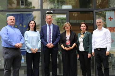 Rektor Akaki Tchelidze, Kanzlerin Natia Shekiladze und Shorena Parunashvili von der (International Relations Managerin) und Gocha Barnovi (Dekan der Fakultät für Theologie) von der Sulkhan-Saba Orbeliani Universität in Tbilisi (Georgien) stehen mit katho-Delegation für ein Gruppenfoto vor dem Eingang der Hochschule.