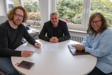 An einem runden Tisch sitzt das Aachener Deakanatsteam. Von links nach rechts: rof. Dr. Dominik Farrenberg, Prof. Dr. Martin Spetsmann-Kunkel und Prof.in Dr.in Silvia Hamacher.