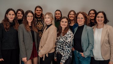 Die Autor_innen der Broschüre stehen für ein Gruppenfoto zusammen und lächeln in die Kamera.