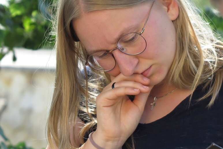 Eine Nahaufnahme einer jungen blonden Frau, die nachdenklich auf den Boden schaut.