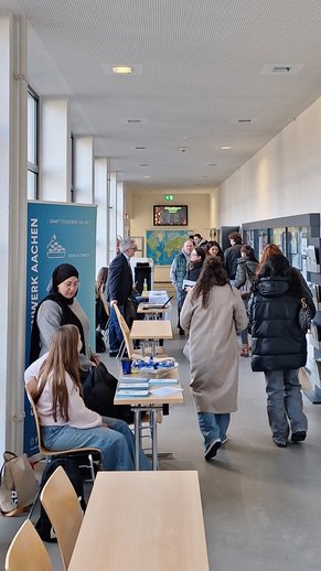 Studieninteressierte im Gespräch gehen an Infostand entlang