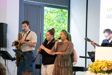 Mehrere Musiker stehen auf der Bühne, eine Frau singt
