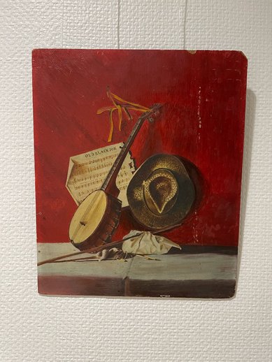 Auf dem Bild sind ein Notenblatt, ein Instrument und ein Hut zu sehen.
