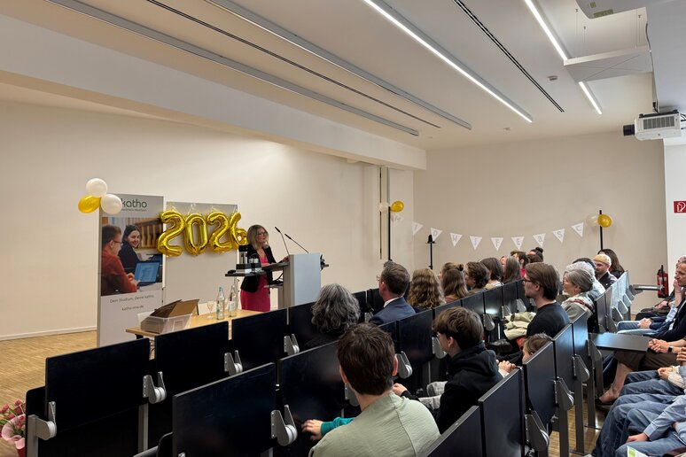 Auf dem Bild sind volle Sitzreihen und die Praxispartnerin am Rednerpult abgebildet