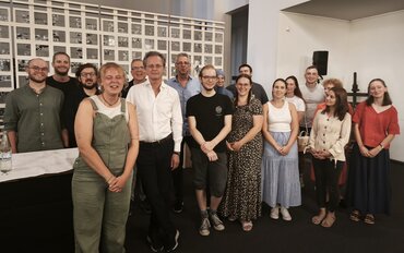 Etwa 15 Weibliche und männliche Personen posieren in zwei Reihen