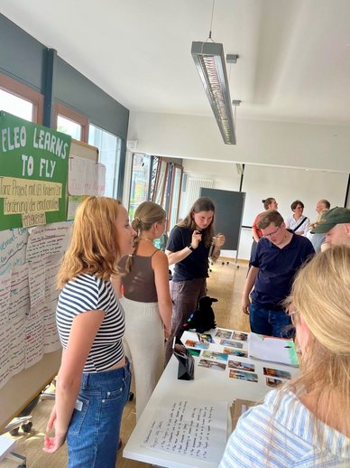 Die Studierenden stellen ihr Tanz-Projekt mit U3 - Kinder zur Förderung der emotionalen Fertigkeiten vor. Teilnehmende schauen sich die ausgestellten Fotos an.