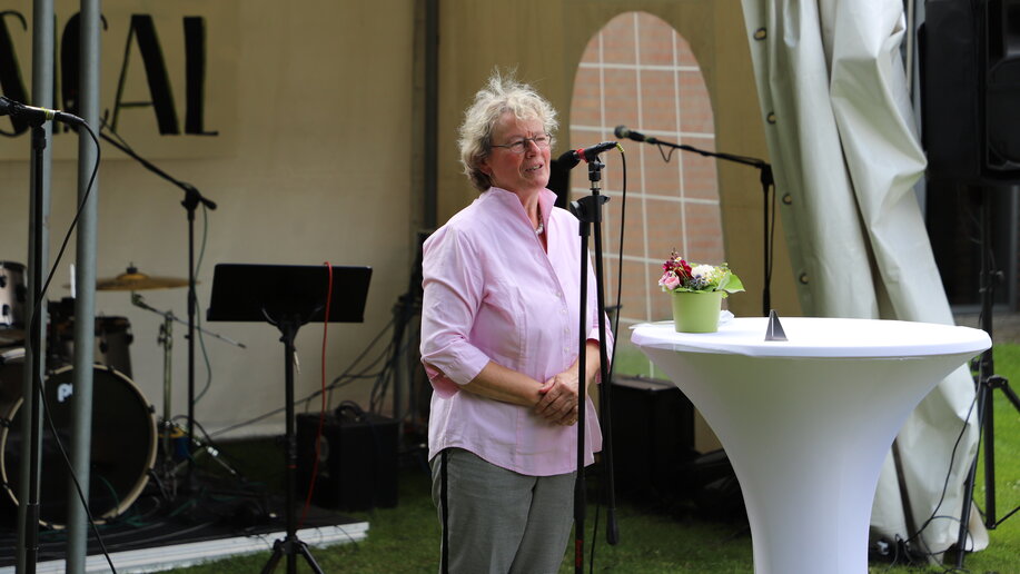 Frau Paß hält eine Rede an einem Tisch.