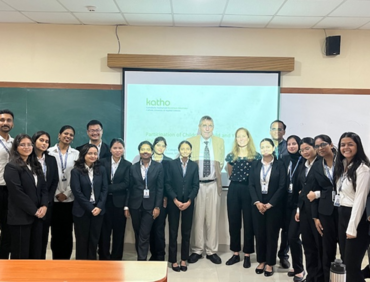 Gruppenfoto in einem Seminarraum. Etwa 18 Personen in formeller Kleidung stehen lächelnd vor einer Tafel und einer projizierten Folie mit grünem „katho“-Logo und dem Titel „Participation of Children and Young …“.
