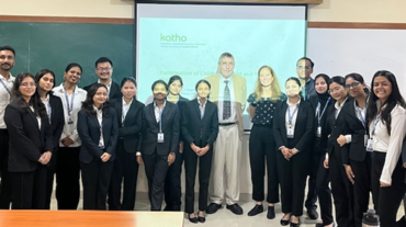 Gruppenfoto in einem Seminarraum. Etwa 18 Personen in formeller Kleidung stehen lächelnd vor einer Tafel und einer projizierten Folie mit grünem „katho“-Logo und dem Titel „Participation of Children and Young …“.