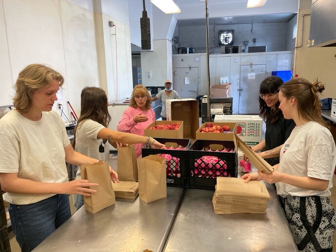 Studierenden packen Lunch-Pakete mit Äpfeln und weiteren zusammen.