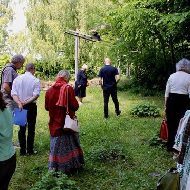 Besucher_innen des Symposiums spazieren im dortigen Alphabetsgarten und suchen die in Beton gegossenen Buchstaben im Gras.