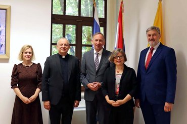 Jasna Ćurković Nimac (Vizerektorin für Internationale Beziehungen), Željko Tanjić (Rektor) und Roberto Antolović (Vizerektor für Wissenschaft) von der Kroatischen Universität für Wissenschaft und Technologie in Zagreb stehen mit der katho-Delegation vor Staatsflaggen in einem Raum..