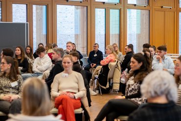 Zahlreiche Tagungsgäste sitzen in einem Seminarraum und hören konzentriert einem Vortrag zu. 