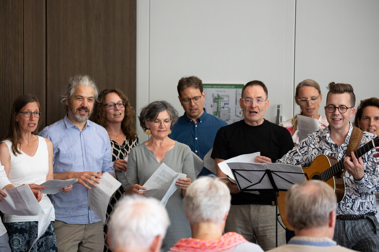 Viele Personen stehen vor- und hintereinander und singen. 