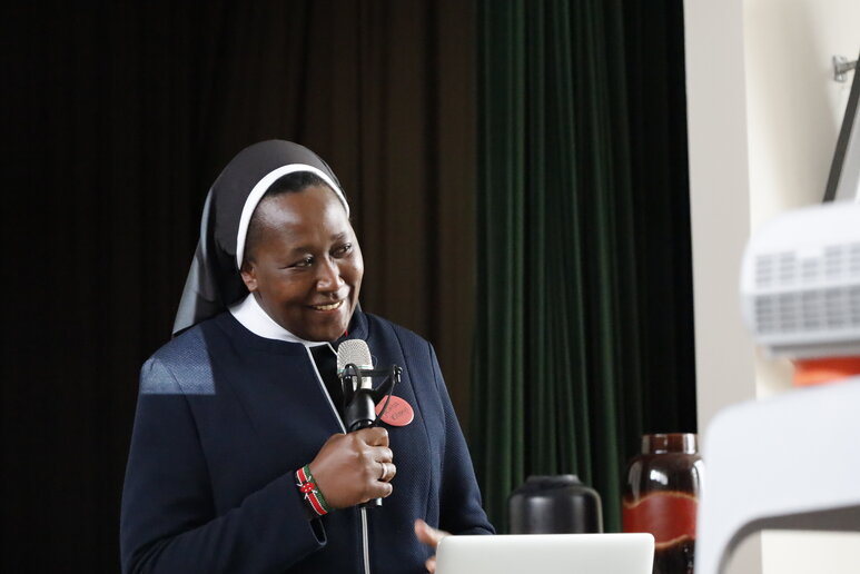 Eine Ordnensschwester redet in ein Mikrophon in ihrer Hand.