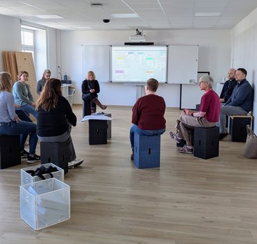 Die Tagungsgruppe sitzen auf mobilen Stühlen in der Transferwerkstatt der katho Paderborn und arbeiten in einer Gruppenphase.