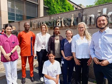 Acht Personen stehen nebeneinander vor der Universitätsklinik Köln
