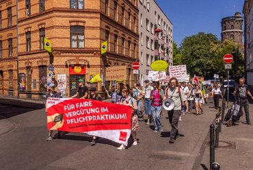 Auf dem Foto ist der Demonstrationszug von der Inititiave am 30.06.2025 zu sehen. Die Teilnehmer_innen halten verschiedene Plakate hoch.