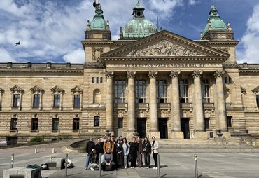 Das Bundesverwaltungsgericht von außen in der Frontalansicht, die Studierenden stehen auf dem Platz davor.