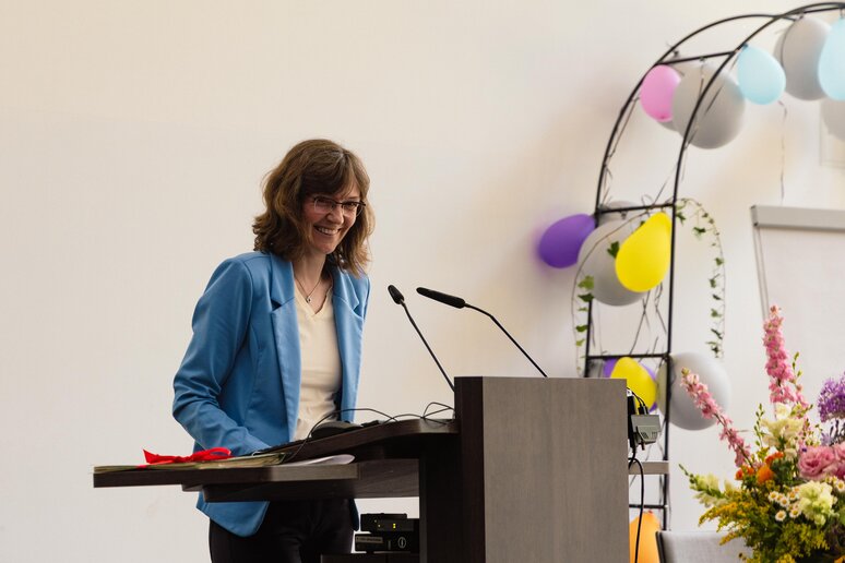 Die Verwaltungsleiterin hält am Rednerpult auf der Bühne eine Rede.