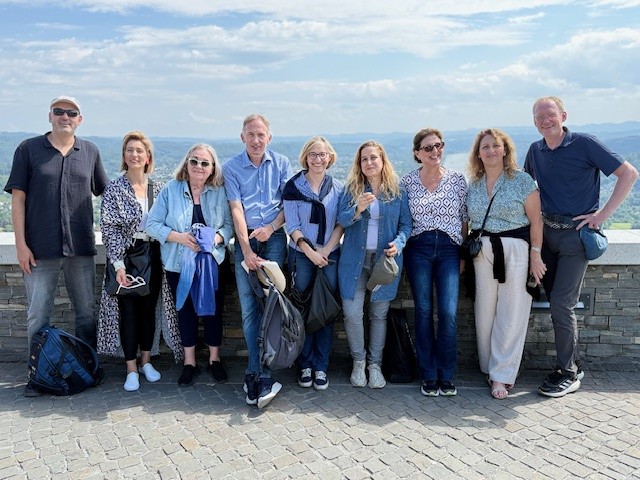 Eine Gruppe von Menschen mit dem Besuch aus Israel stehen auf dem Drachenfels und lächelt in die Kamera. Im Hintergrund ist blauer Himmel zu sehen.