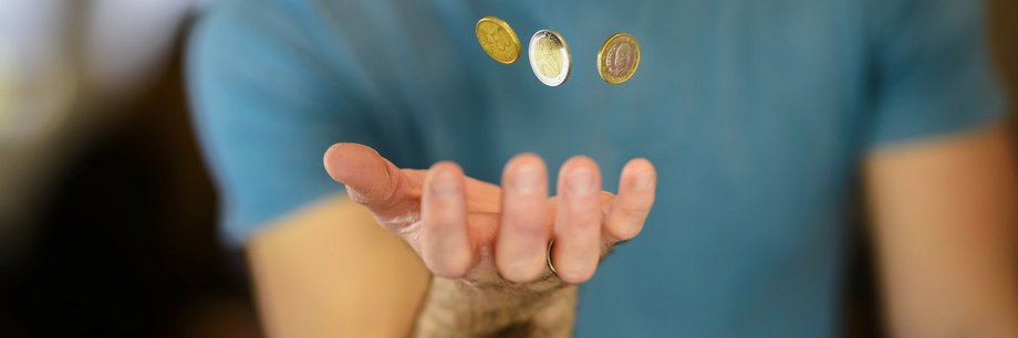 Mann fängt Geldmünzen mit der Hand auf