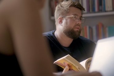 Ein Student mit Bart sitzt im Seminar an einem Laptop.