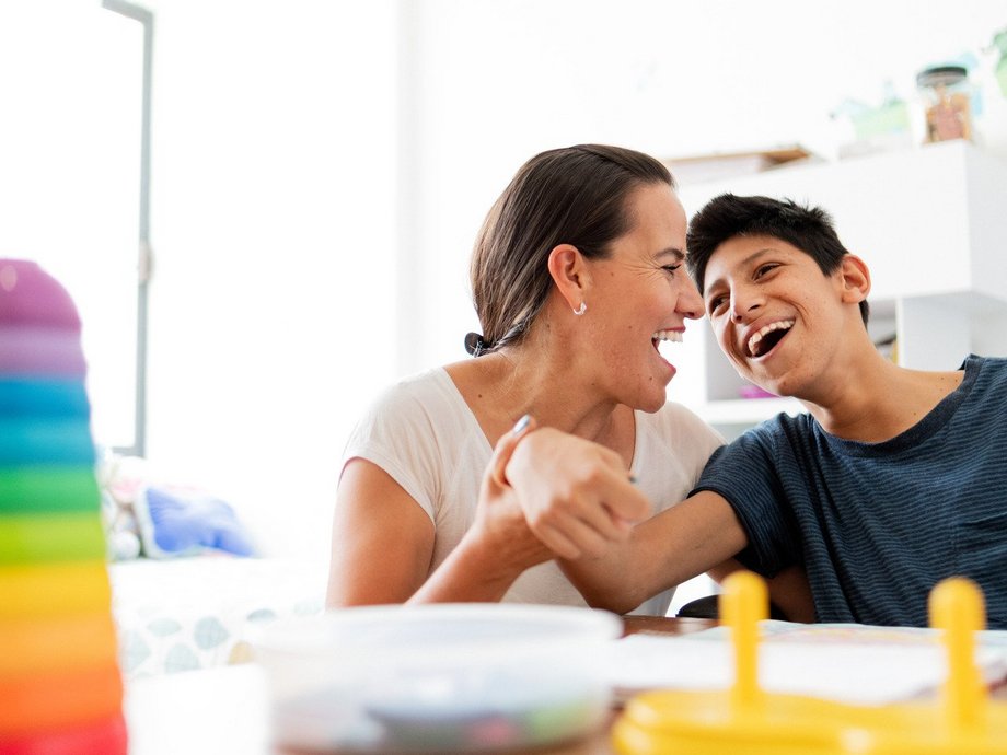 Eine Mutter lacht gemeinsam mit ihrem Sohn, dieser hat eine Zerebralparese.