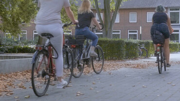 Einige Studierende fahren mit dem Fahrrad in Richtung der Fahrradständer am katho-Gebäude in Münster
