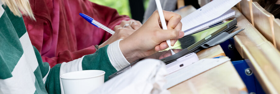 Studierende notieren sich etwas während eines einer Vorlesung.