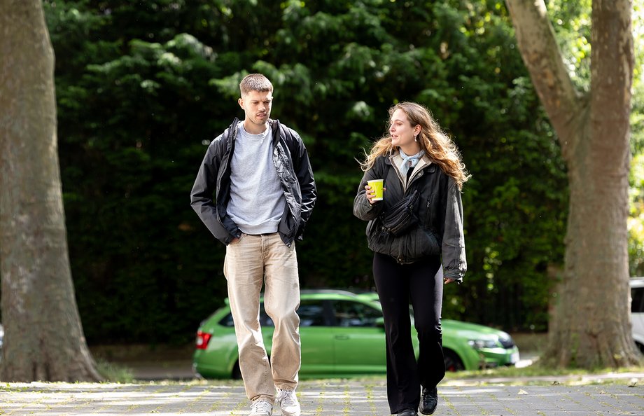 Zwei Studierende laufen einen Weg entlang und reden miteinander.