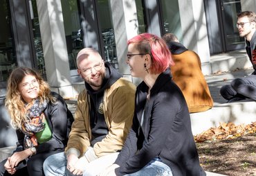 Mehrere Studierende sitzen im Außengelände zusammen.