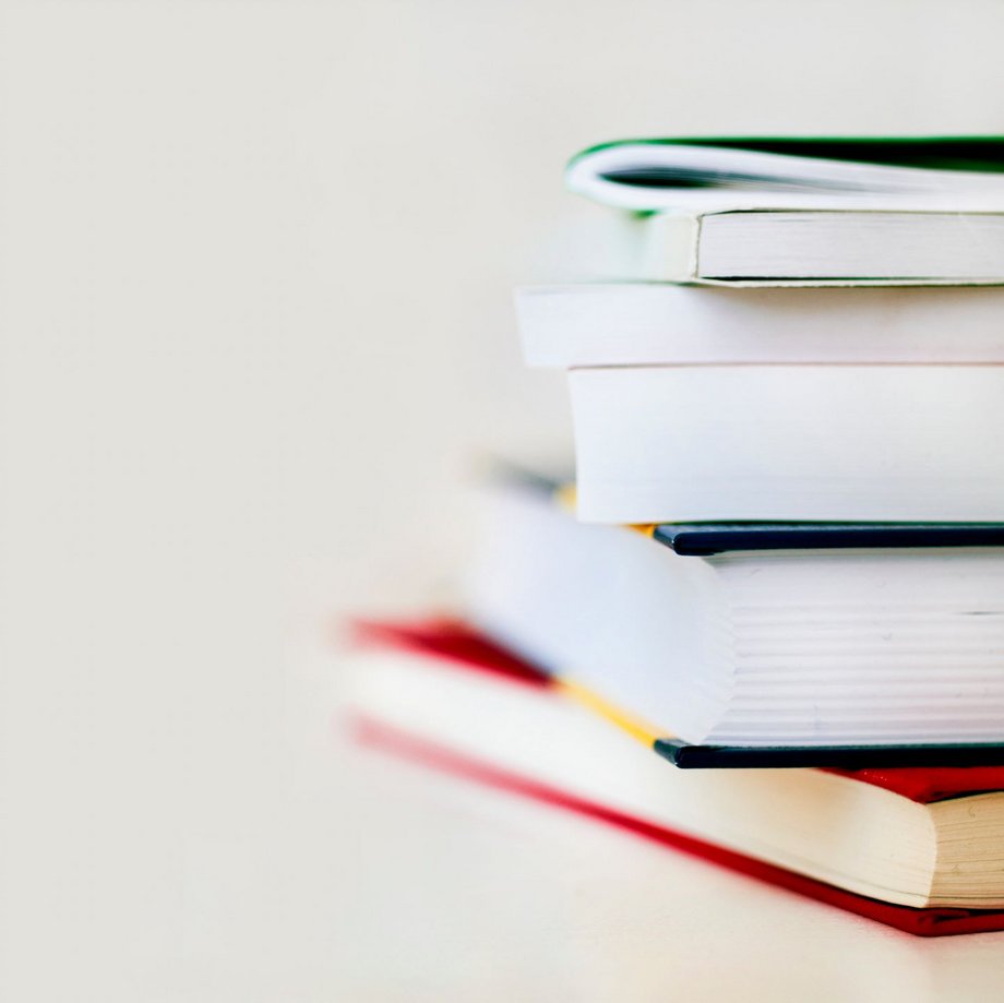 Kleiner Bücherstapel vor weißem Hintergrund.

