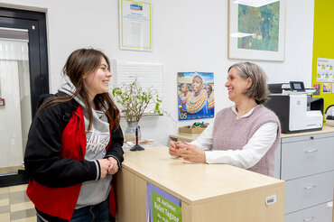 Eine Mitarbeiterin aus dem Studierendensekretariat unterhält sich mit einer Studentin.