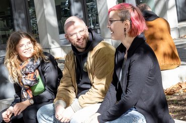 Mehrere Studierende sitzen im Außengelände zusammen.