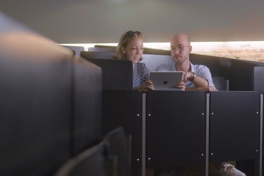 Zwei Studierende sitzen im Kölner Audimax und schauen auf ein Tablet.