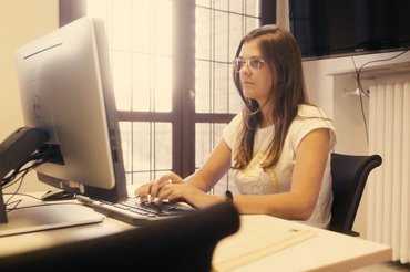 Eine Studentin sitzt konzentriert in einem Lernraum an einem Computer.