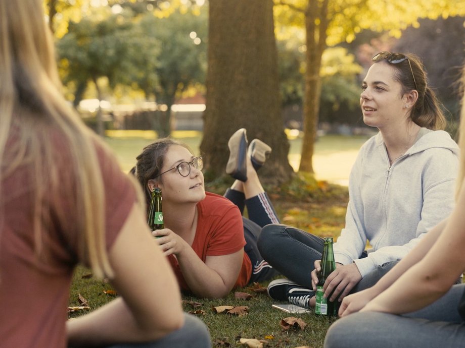 Eine Gruppe junger Studentinnen sitzt im Park in Paderborn und unterhält sich.